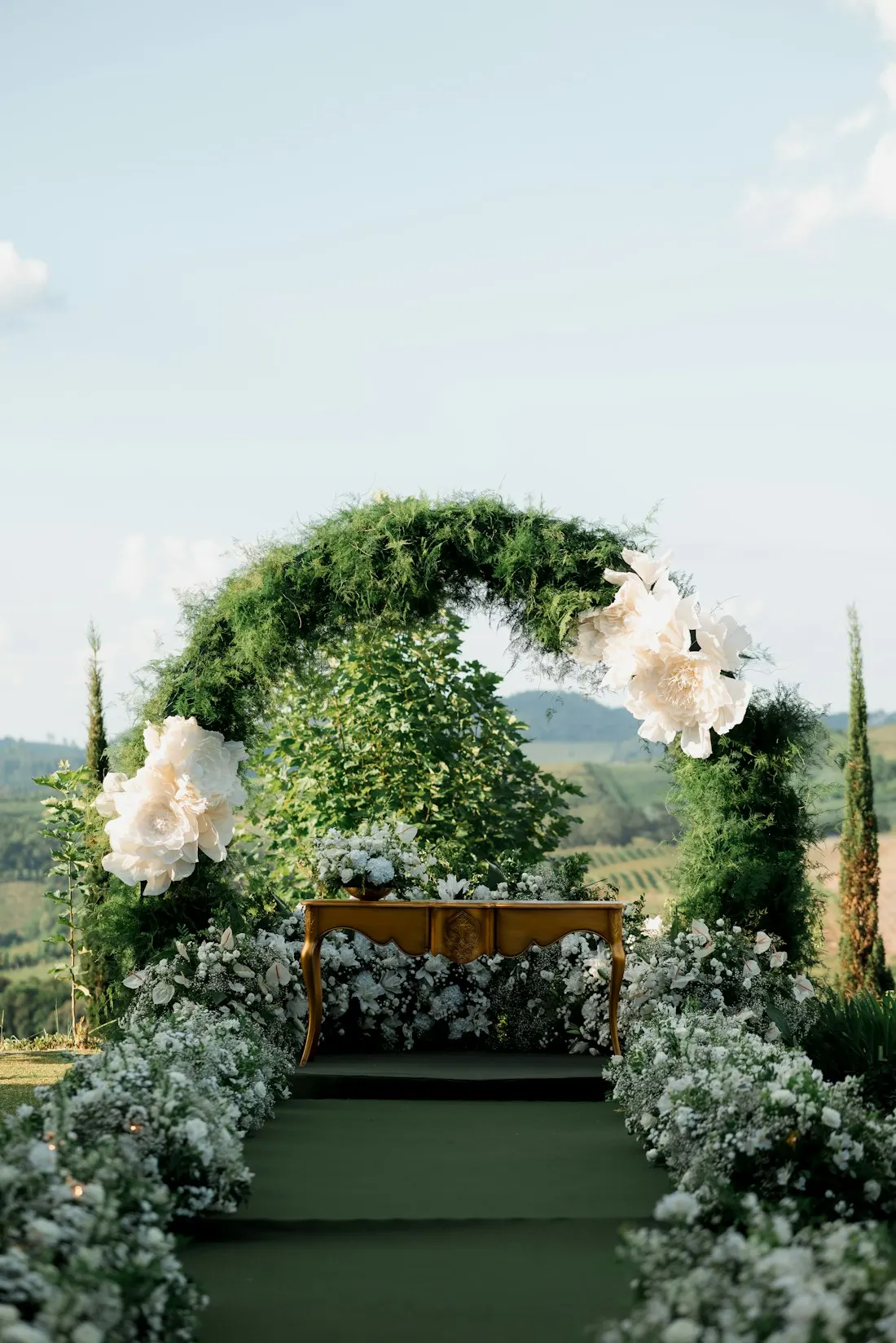 Altar ao ar livre com arco de folhagens e flores brancas