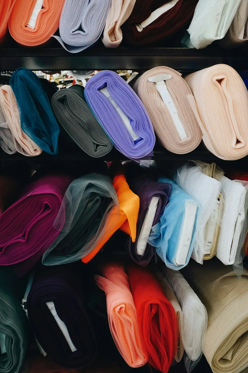 Rolos de tecido colorido organizados numa prateleira