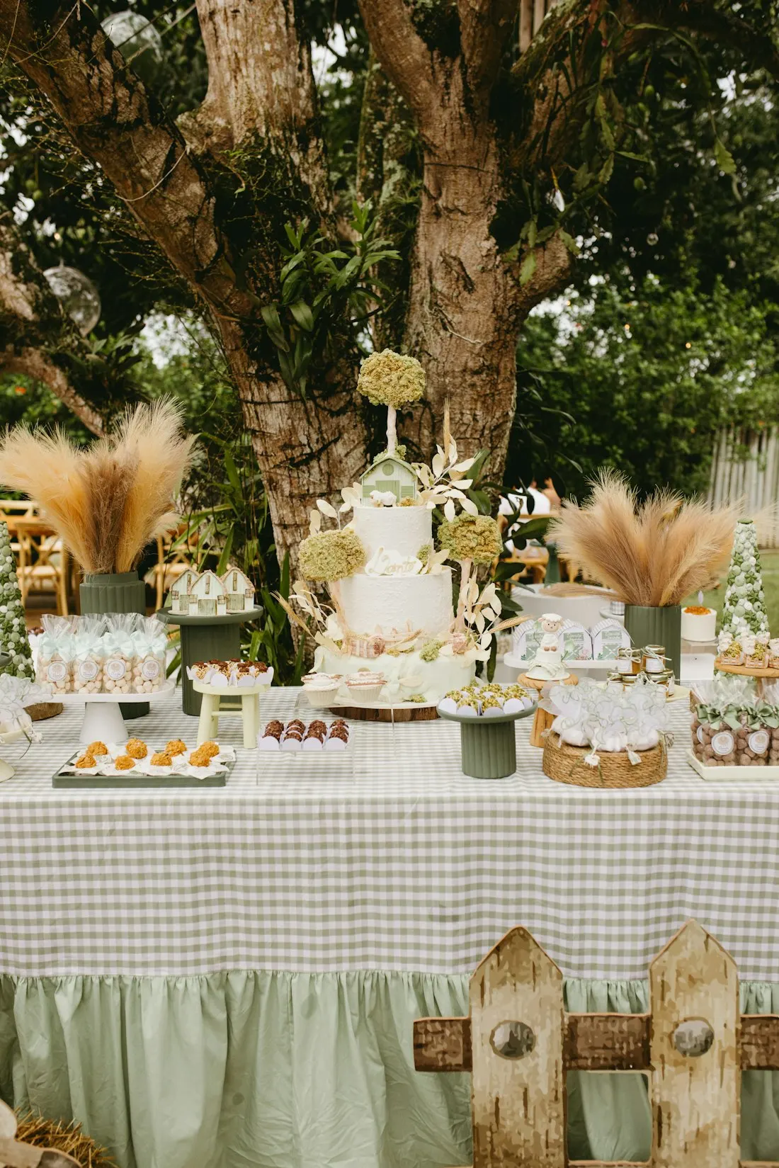 Mesa de doces ao ar livre em tons neutros, com capim seco e madeira